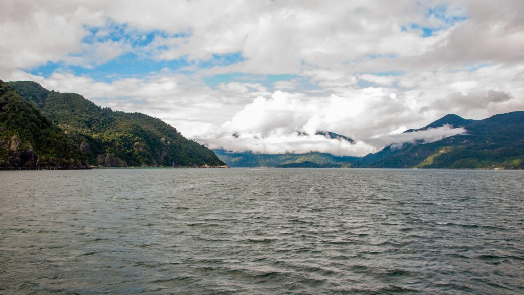 Bras de mer encadré de collines boisées, nuages bas accrochés aux versants