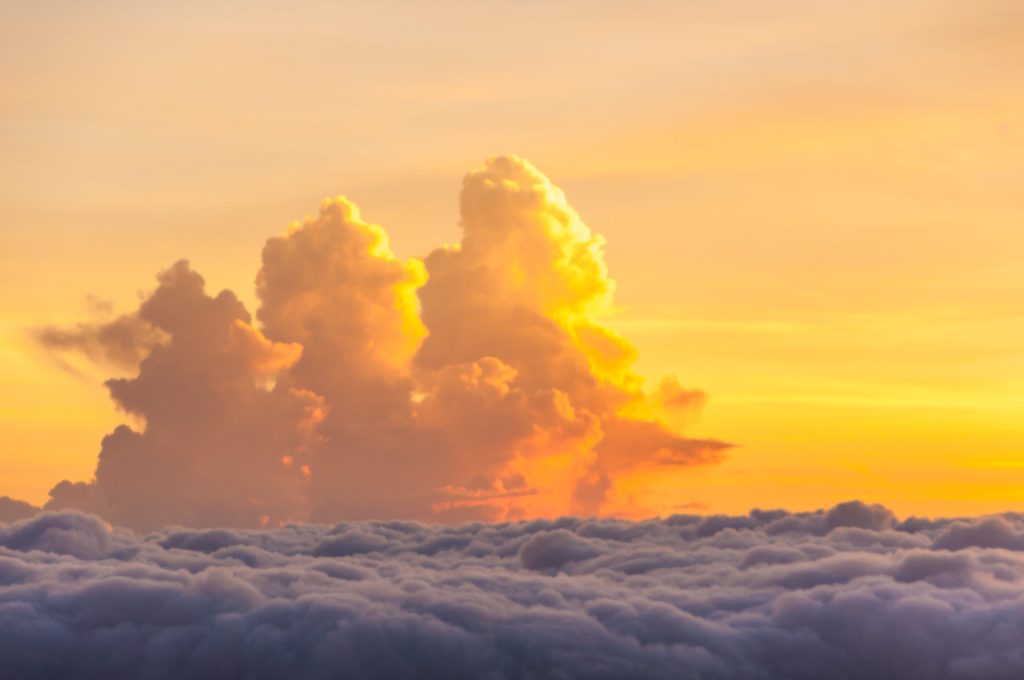 Cumulus dorés illuminés par le soleil couchant émergeant d'une mer de nuages
