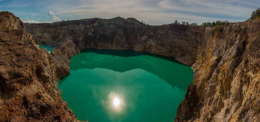 Panoramique du lac de cratère vert émeraude du Kelimutu cerné de parois ocre