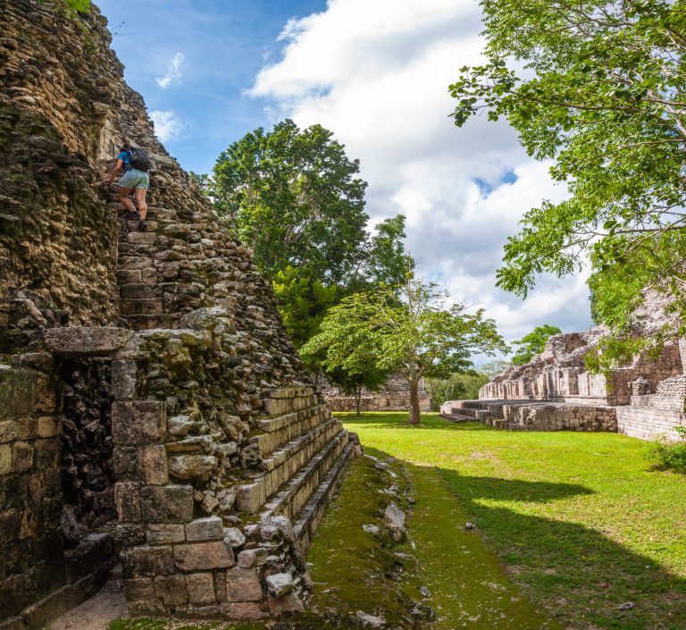 Visiteuse gravissant l'escalier raide d'une pyramide maya envahie par la végétation