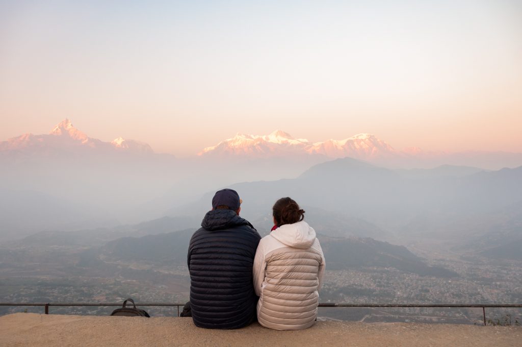 Couple assis de dos contemplant la chaîne des Annapurna rosie par le lever du soleil