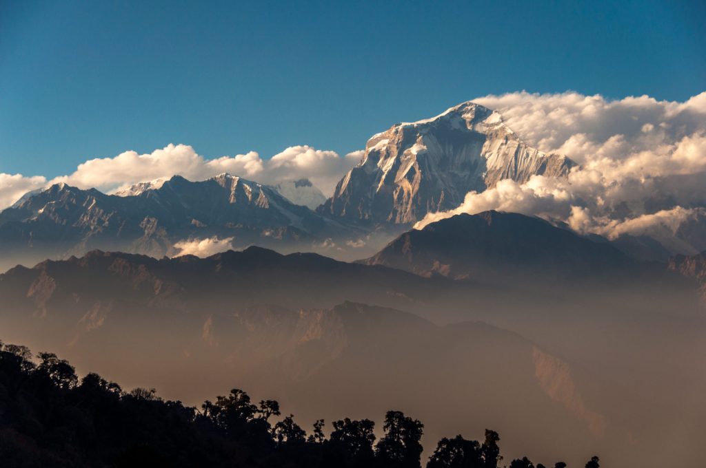 Sommet massif du Dhaulagiri émergeant d'une couronne de nuages au-dessus de vallées brumeuses