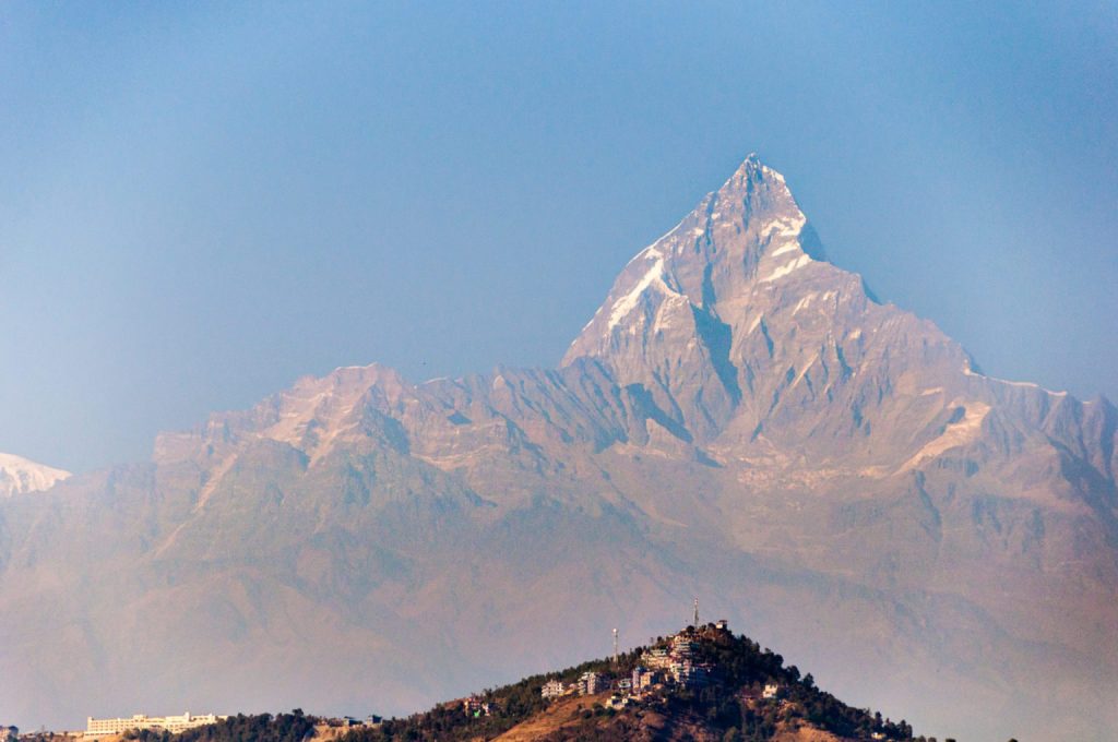 Sommet pyramidal du Machapuchare surplombant la brume et les collines de Pokhara