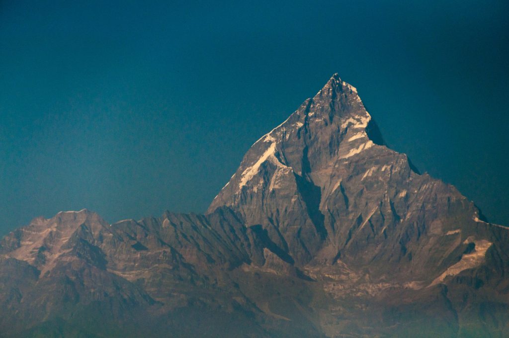 Arête effilée du Machapuchare éclairée au soleil rasant sur fond de ciel bleu profond
