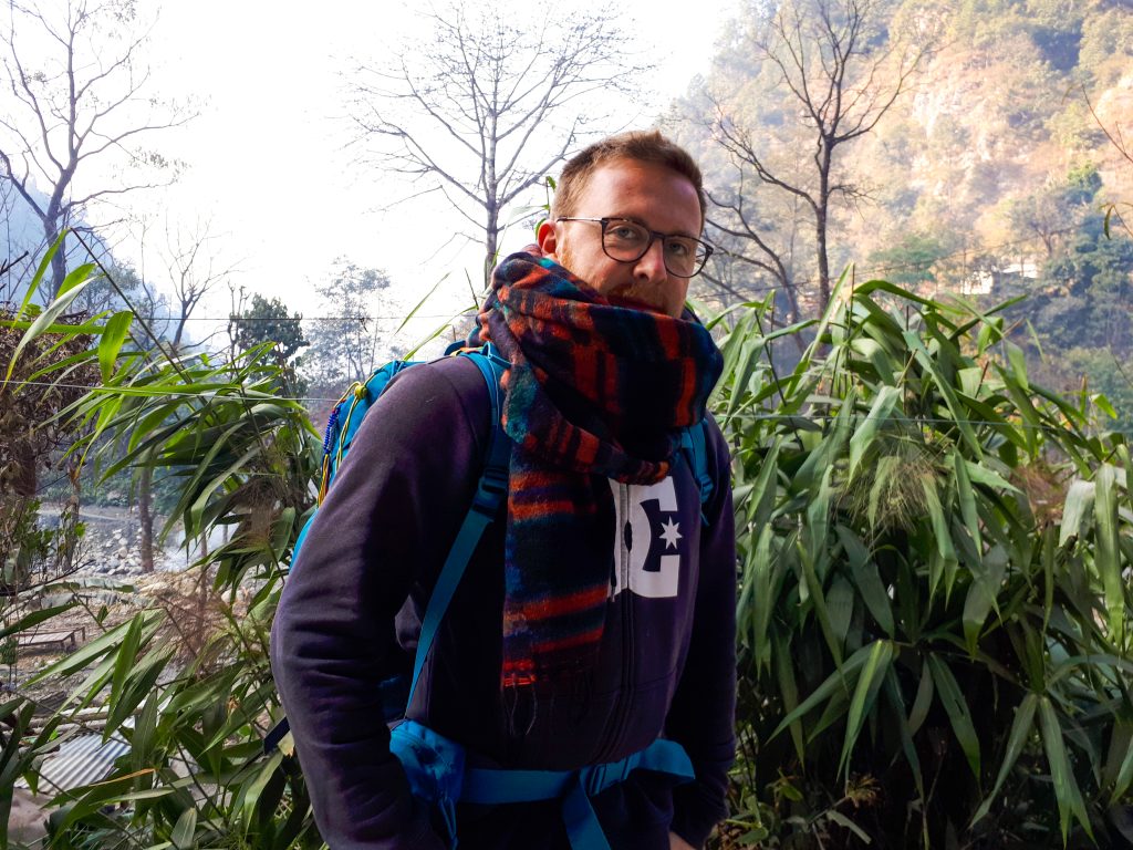 Portrait d'un randonneur, écharpe colorée et sac à dos, dans une vallée himalayenne