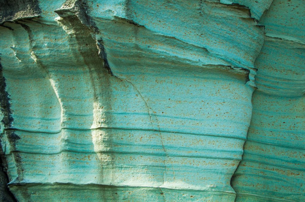 Paroi rocheuse aux strates turquoise mouchetées d'ocre